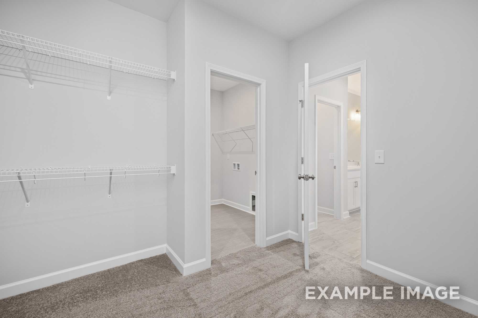 Spacious master suite laundry and walk-in closet in The Cypress D II, featuring wire shelving, washer hookups, and open doorways