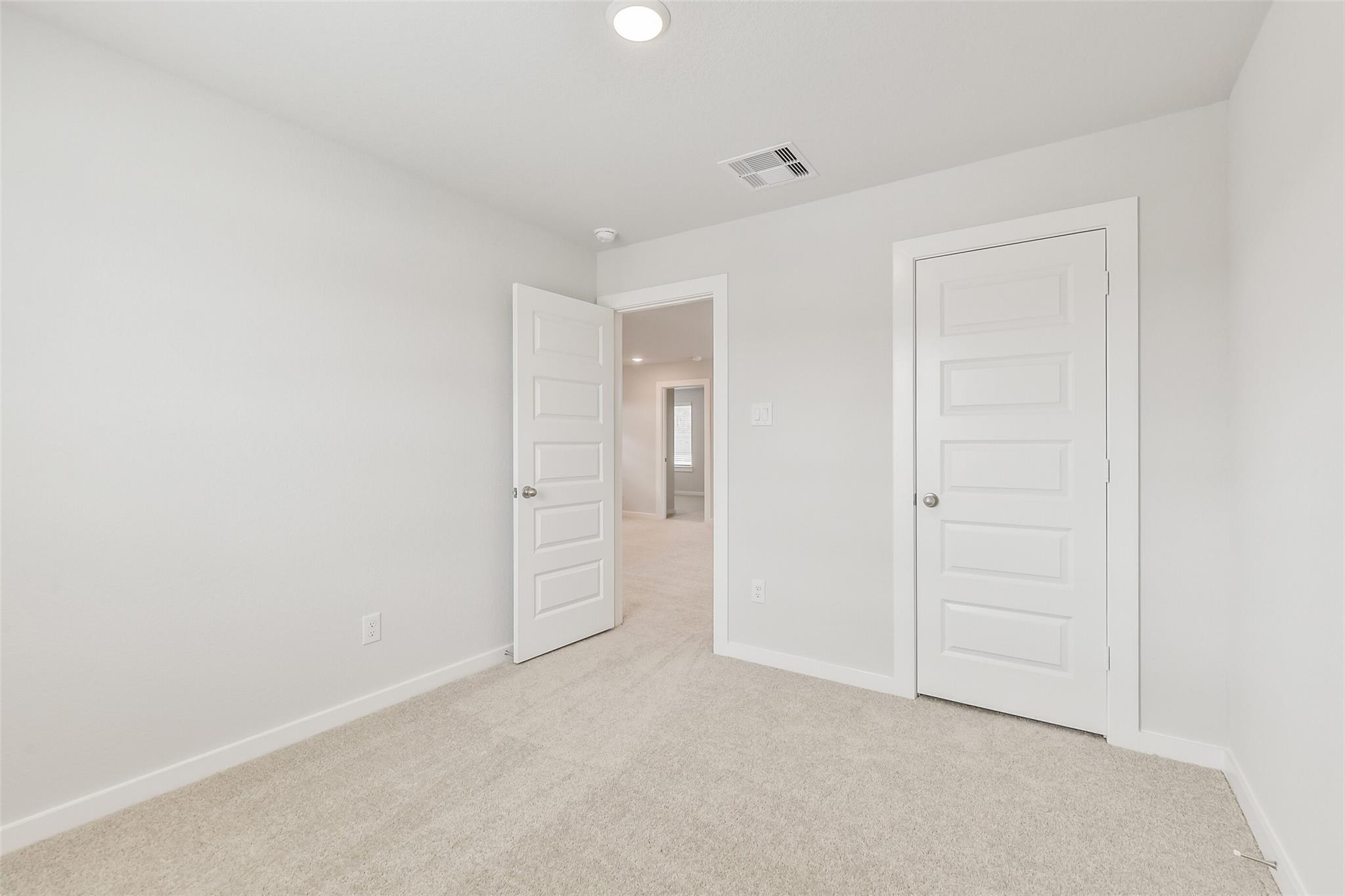 Spacious secondary bedroom with open doors to hallway and bath in Davidson Homes The Brazos E, Cleveland, Texas