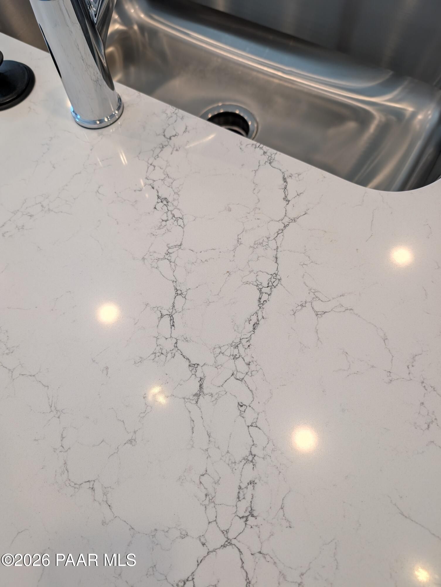 White quartz countertop with stainless steel sink and chrome faucet in Davidson Homes The Sheridan II G, Prescott, Arizona