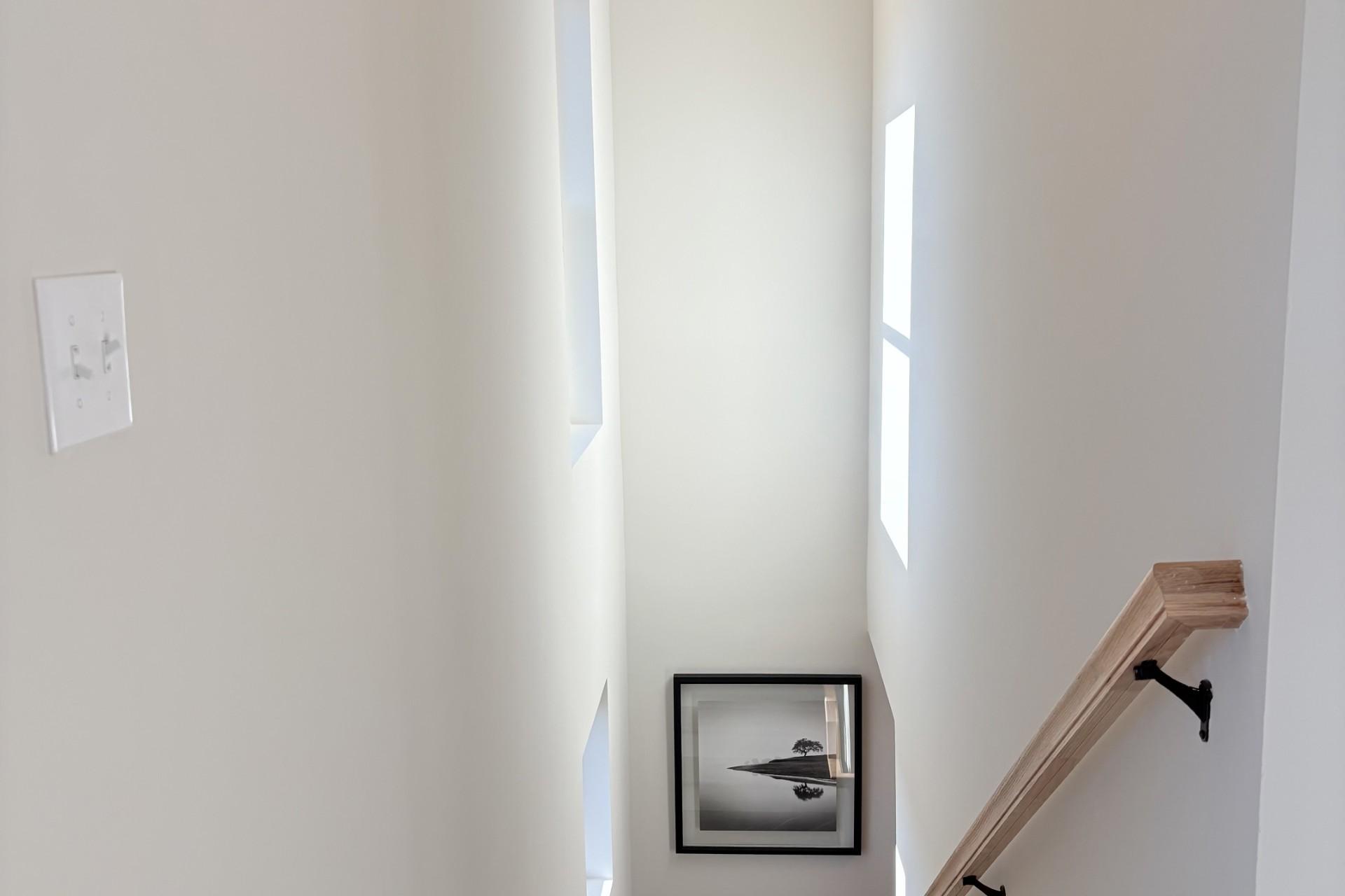 Elegant oak staircase with white walls, framed photo, and window in Hemingway home, Cumming GA by Davidson Homes