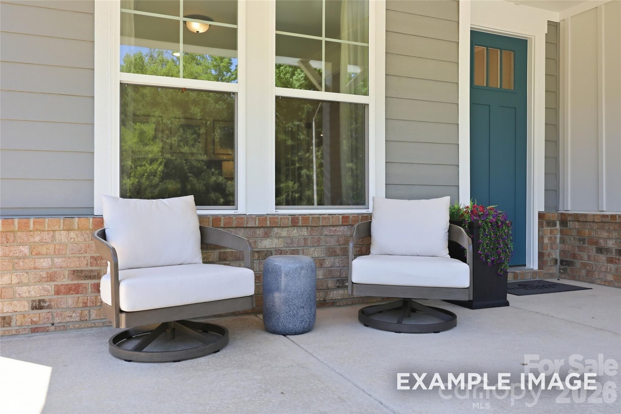 Inviting front porch with swivel lounge chairs and teal door at Davidson Homes The Aspen B in Windgate, Mooresville, NC
