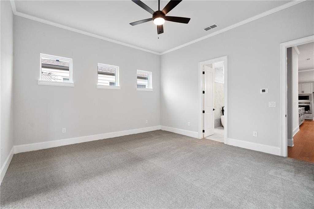 Spacious master bedroom with gray carpet, ceiling fan, three windows, and en-suite bath in Davidson Homes Seaside B, Woodstock, GA