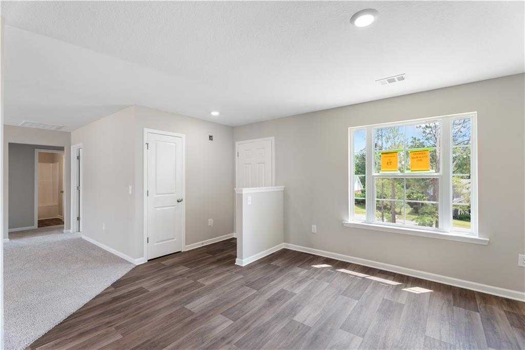 Open living space with light wood floors, neutral walls, and large window in The Washington 3-bedroom home, Phenix City, Alabama