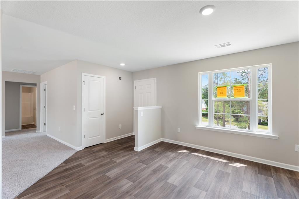Open living space with light wood floors, neutral walls, and large window in The Washington 3-bedroom home, Phenix City, Alabama