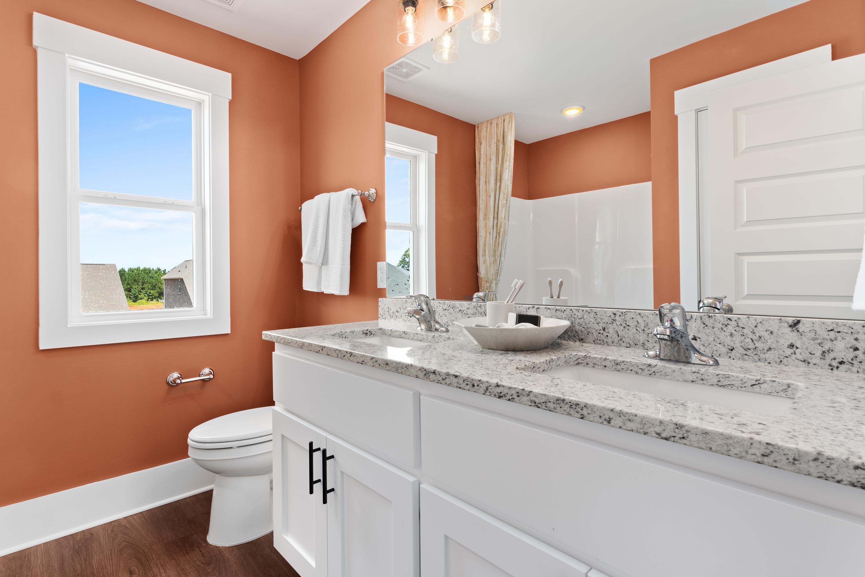 Spacious upper-floor master bathroom in The Shelby A with terracotta walls, double white vanity, quartz counters, and scenic window