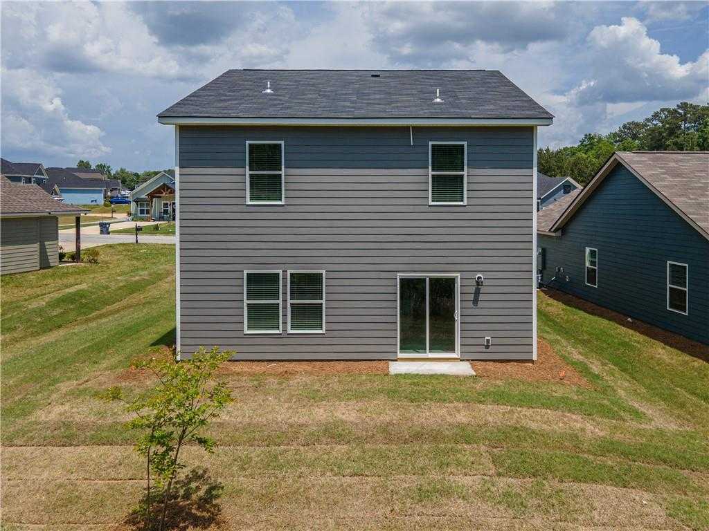 Rear view of two-story gray The Bartlett home with sliding glass door and backyard patio in Summer Vineyard, Phenix City, Alabama