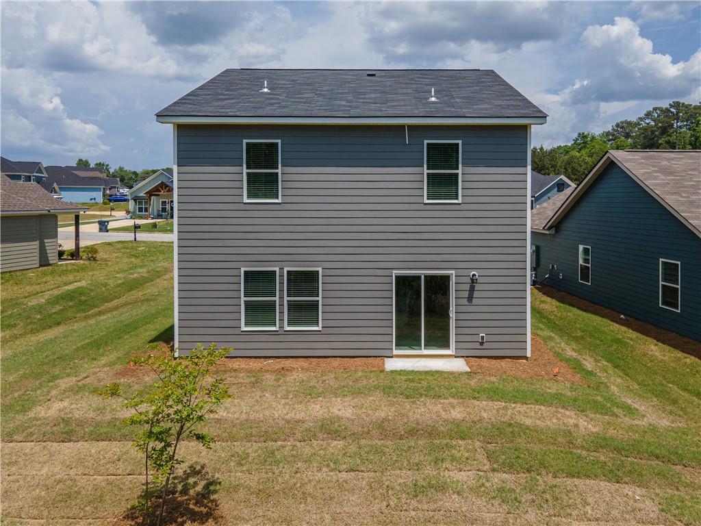 Rear view of two-story gray The Bartlett home with sliding glass door and backyard patio in Summer Vineyard, Phenix City, Alabama