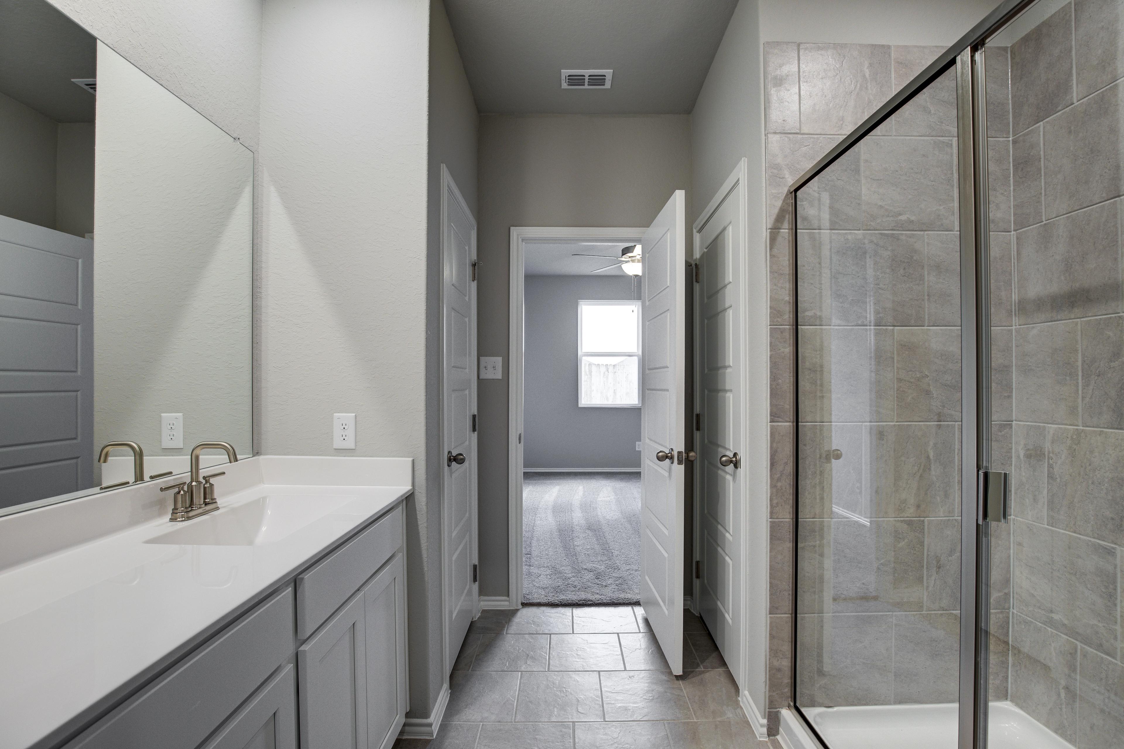 Spacious master bathroom in The Blanco C by Davidson Homes featuring double vanity, glass walk-in shower, and neutral tile