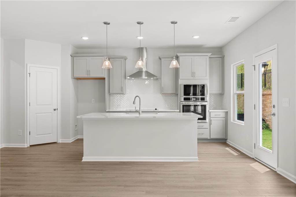 Modern kitchen with white island, gray cabinets, and stainless appliances in The Burton A home at The Bluffs, Canton, GA.