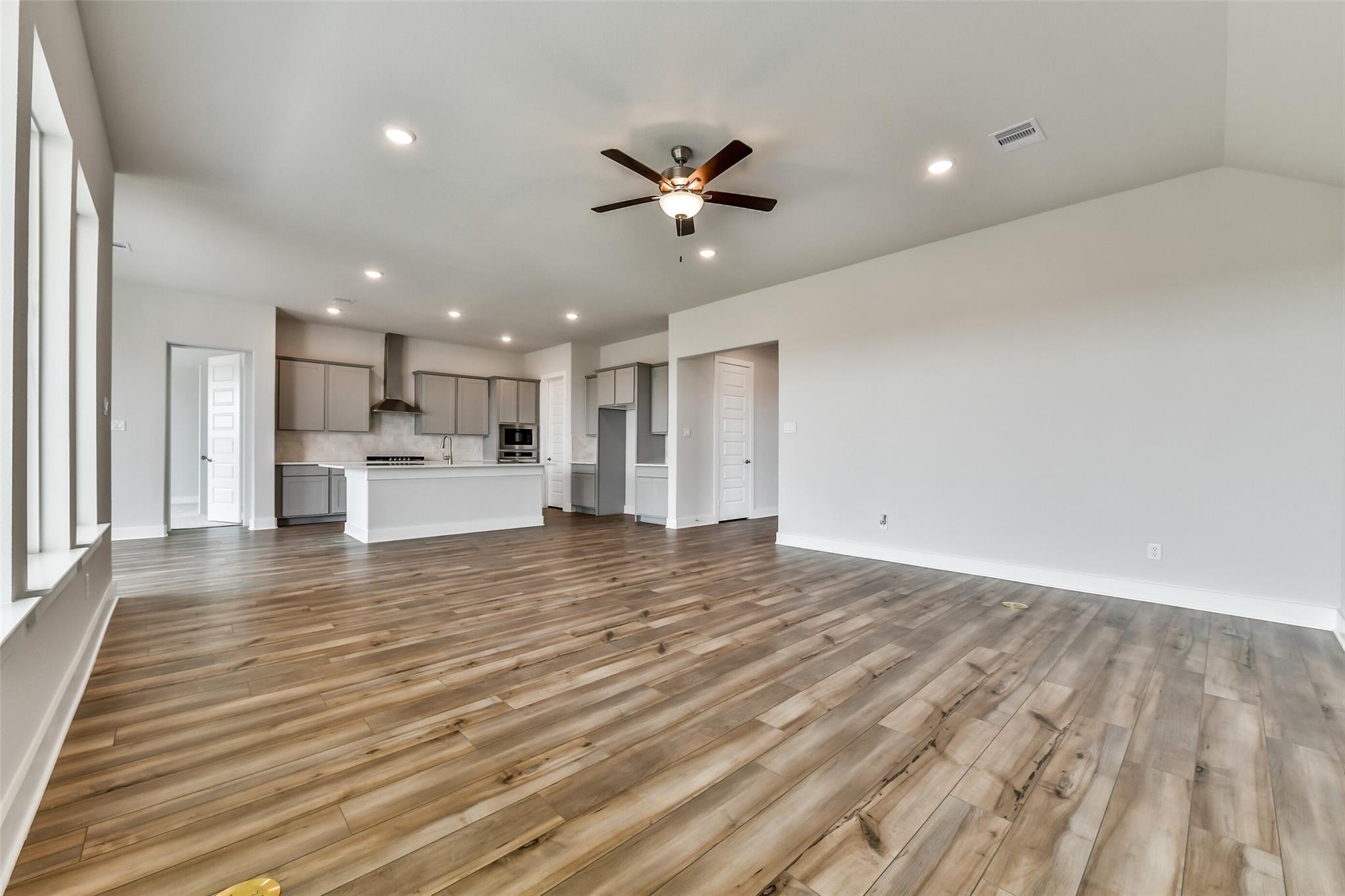 Open-concept living room with hardwood floors, white cabinets, and ceiling fan in Davidson Homes The George A, Lago Mar, Texas City