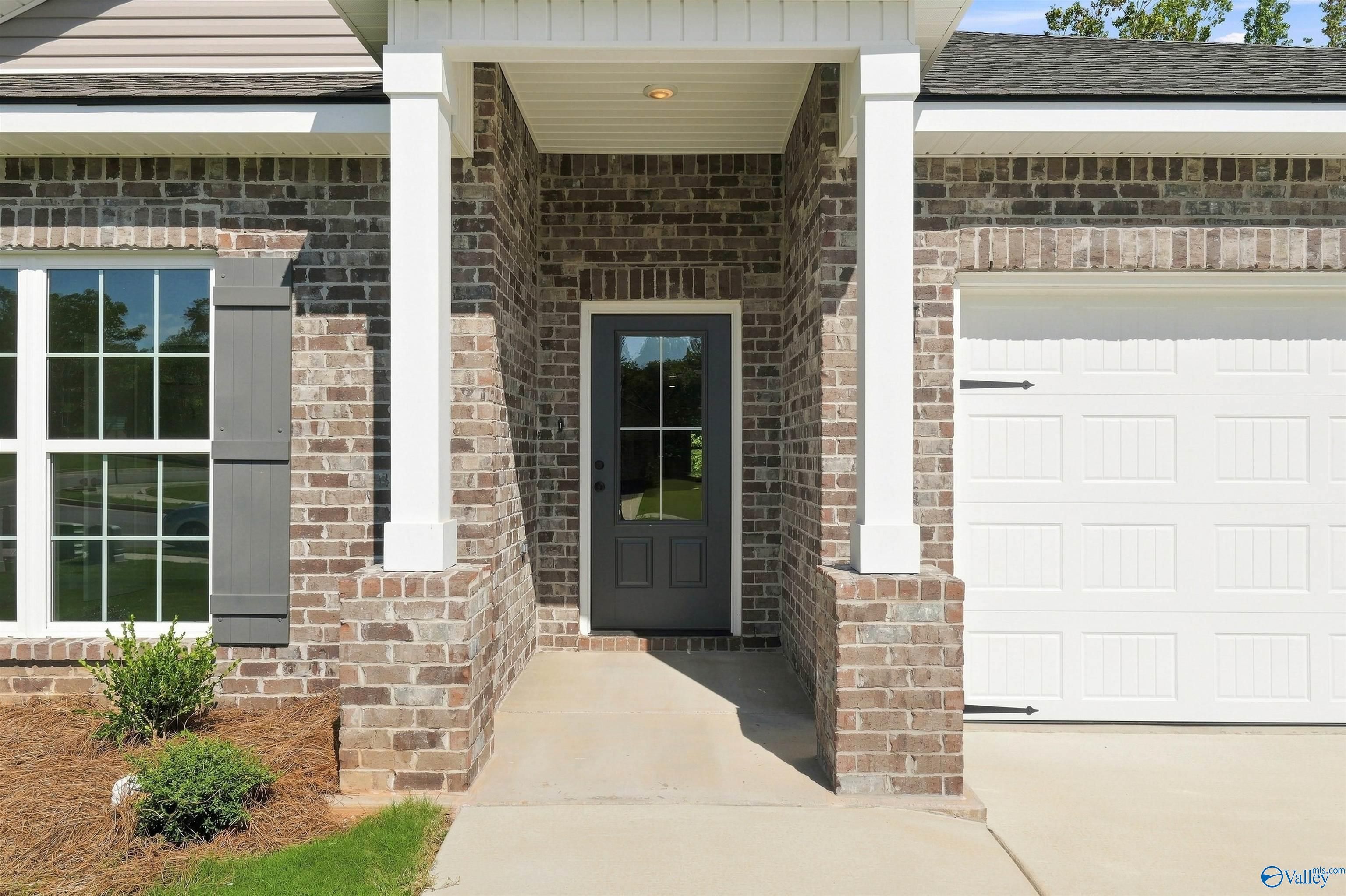 Brick exterior with covered front porch and two-car garage at The Daphne floor plan home in Spragins Cove, Huntsville, AL.