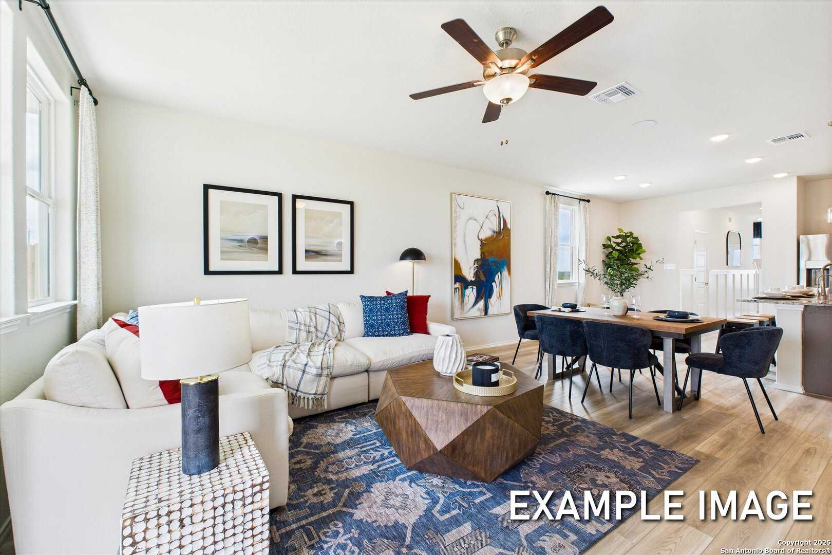 Modern open living and dining area with white sectional sofa, geometric coffee table, and blue rug in Davidson Homes The Brazos C, San Antonio