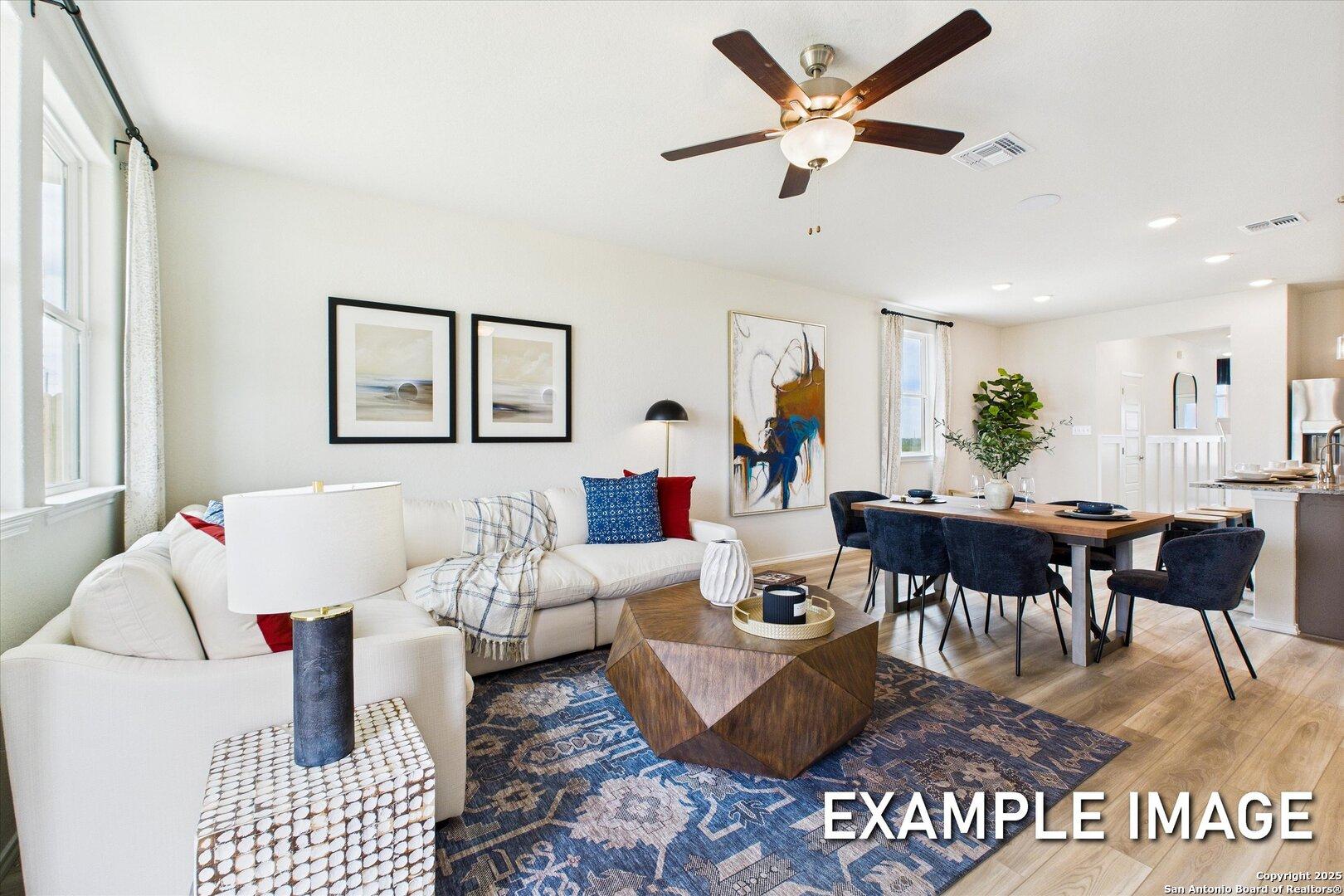 Modern open living and dining area with white sectional sofa, geometric coffee table, and blue rug in Davidson Homes The Brazos C, San Antonio