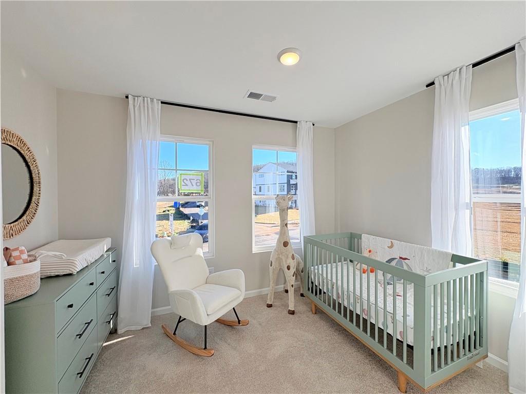 Cozy nursery with giraffe crib, white rocking chair, changing table in The Durham D home, Cumming, GA