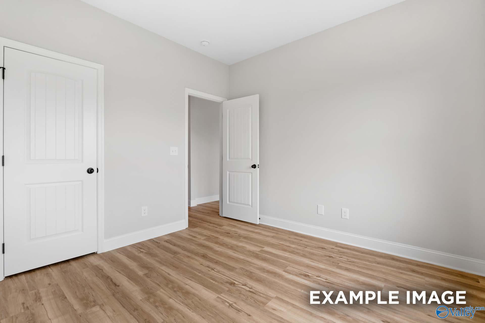 Bright bedroom with wood-look flooring and white interior doors in The Shelby B floor plan at Jaguar Hills, Huntsville.