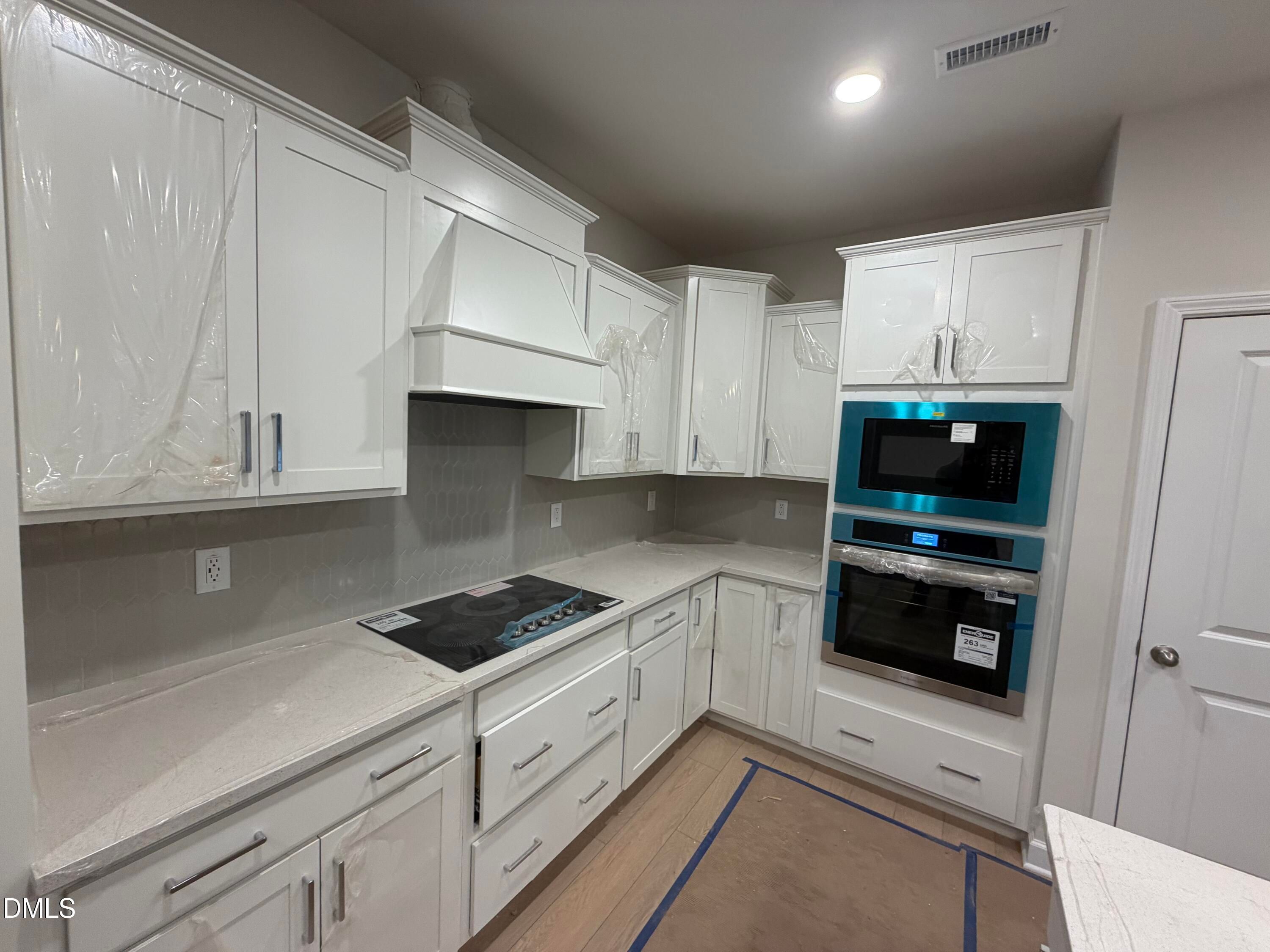 Modern white shaker kitchen with quartz counters, stainless double ovens, gas cooktop in Davidson Homes The Daphne C, Lillington, NC