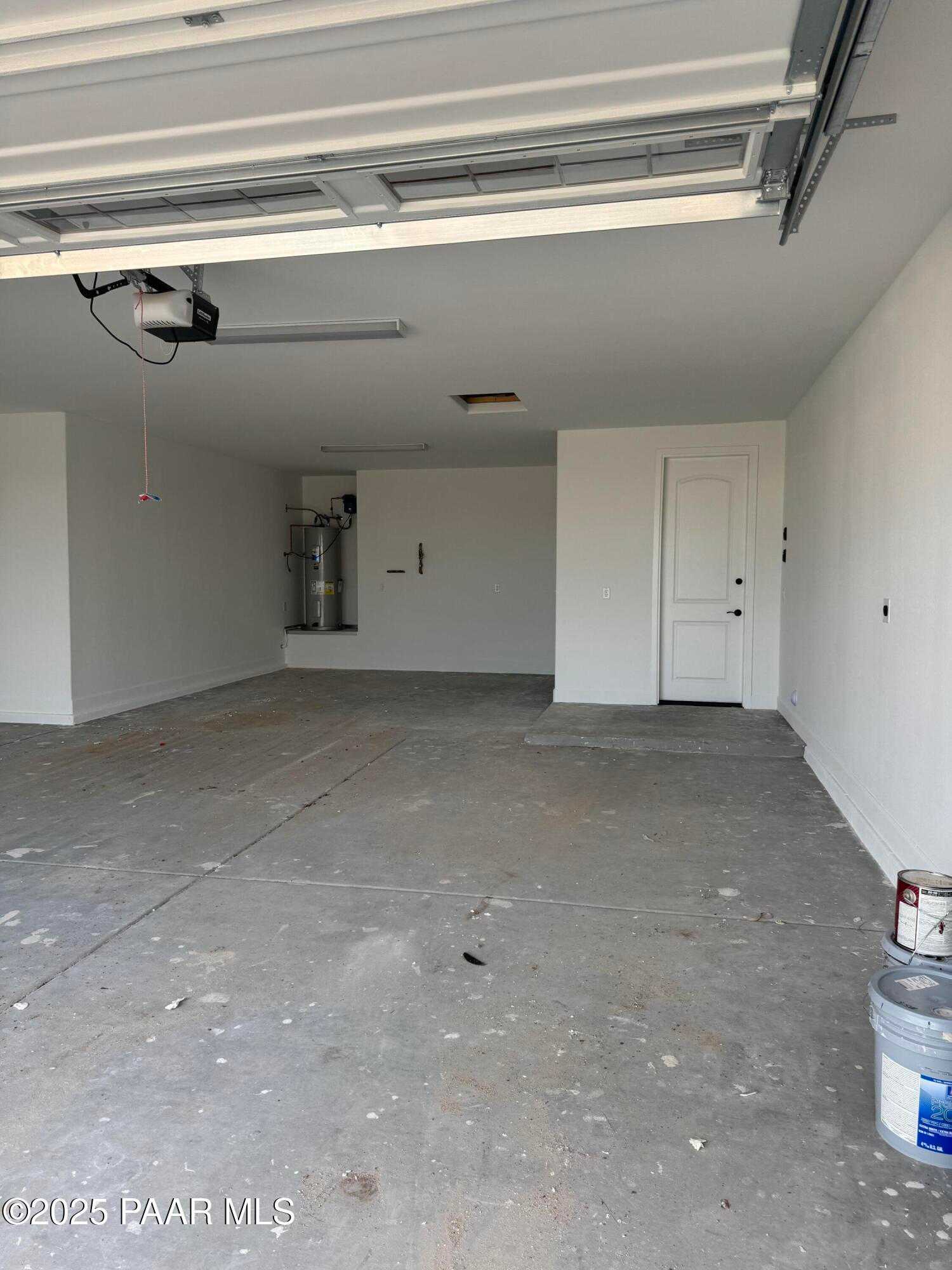 Spacious 4-car garage with white walls, open doors, and concrete floor in Evermore Homes The Sunrise A, Prescott Valley, Arizona