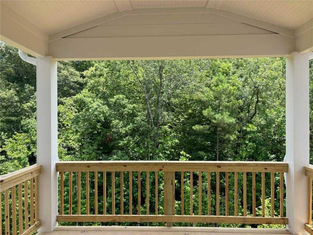 Covered back deck with white columns and wooden railing overlooking lush Georgia forest in Davidson Homes 5-bedroom residence, Riverwood, Dallas