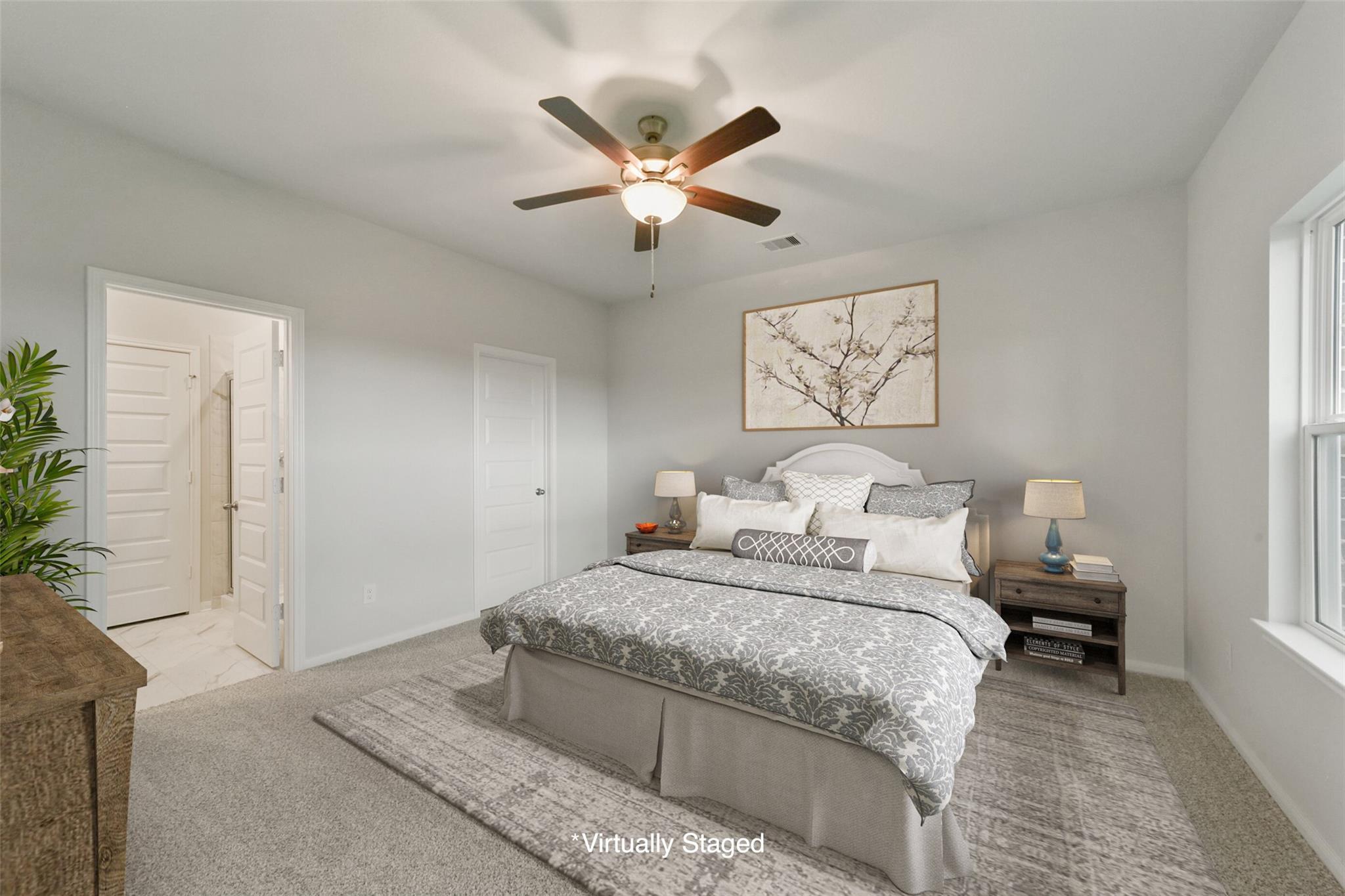 Serene master bedroom with gray upholstered bed, ceiling fan, and en-suite bath in Davidson Homes San Marcos E, Beasley, Texas
