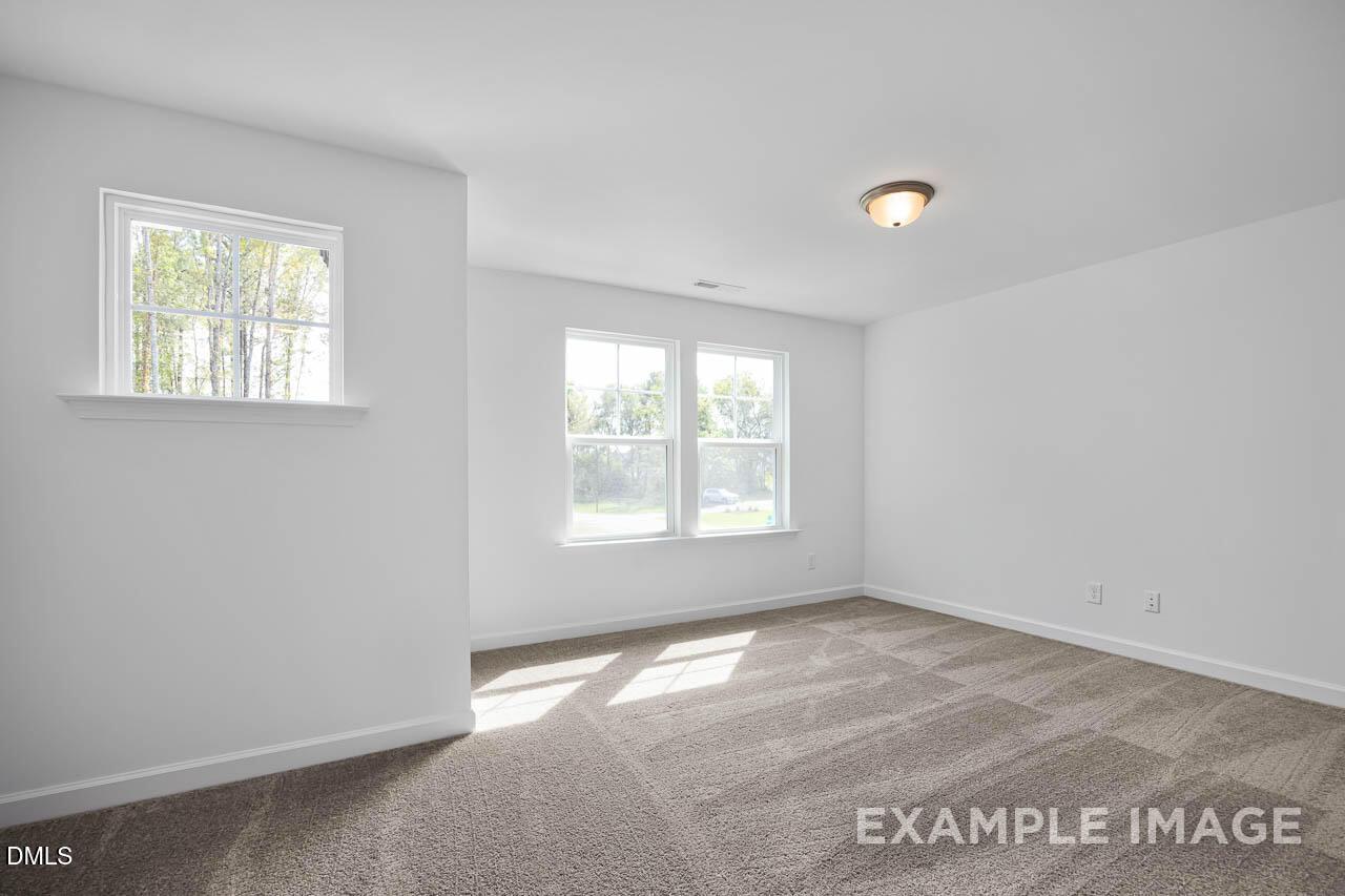 Bright secondary bedroom with large windows, white walls, and beige carpet in Davidson Homes The Willow D, Zebulon, NC