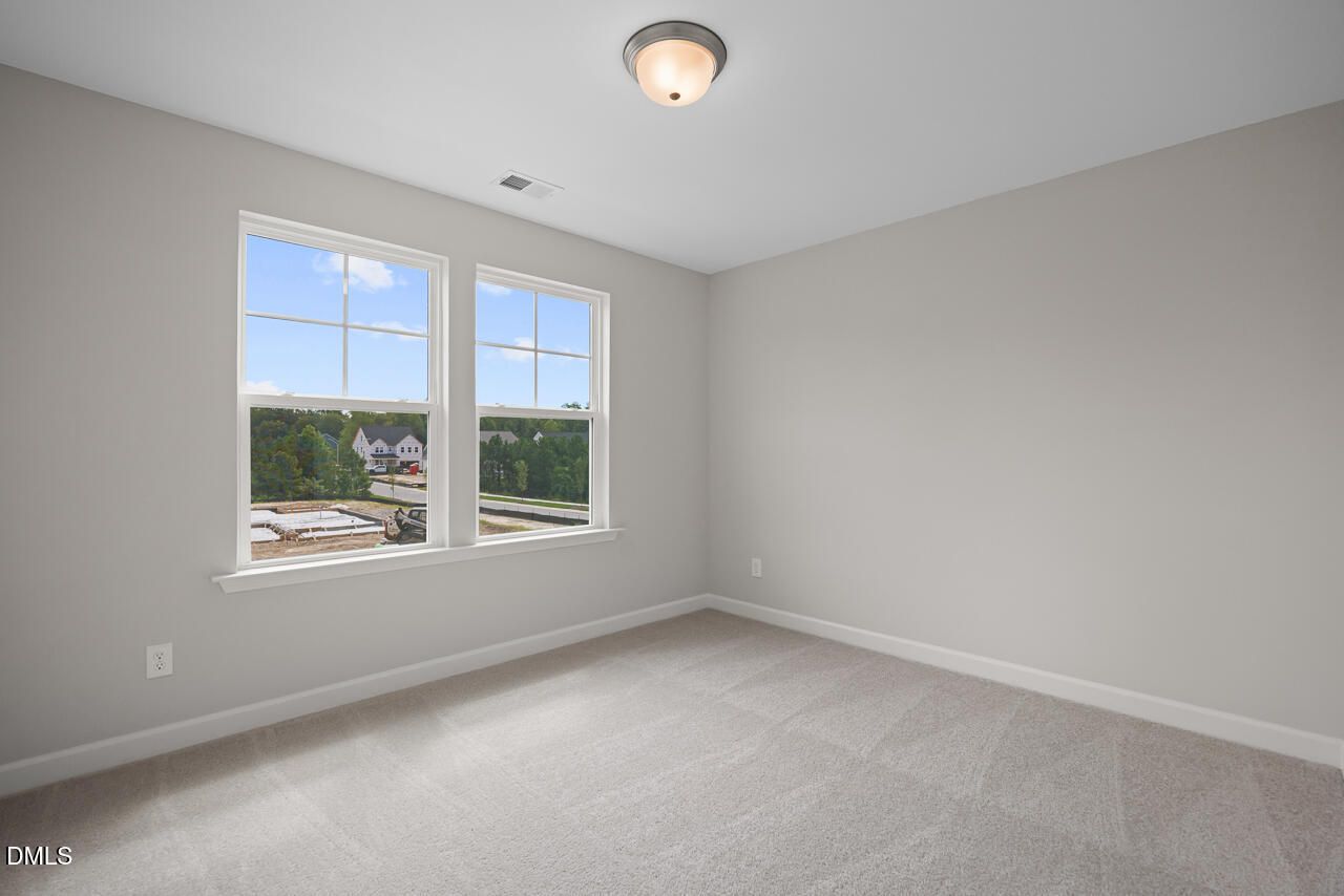 Bright, carpeted bedroom with large windows in The Chestnut floor plan at Wendell Ridge, Wendell, North Carolina.