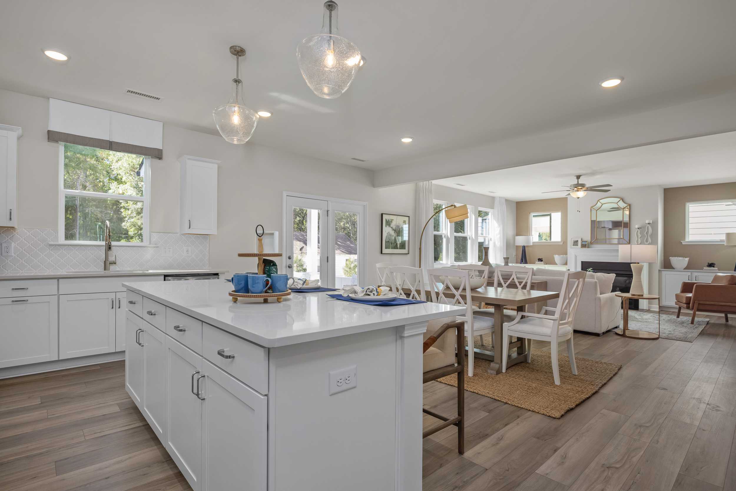 Spacious open-concept kitchen and dining in The Hickory II E with white island, pendant lights, and hardwood floors