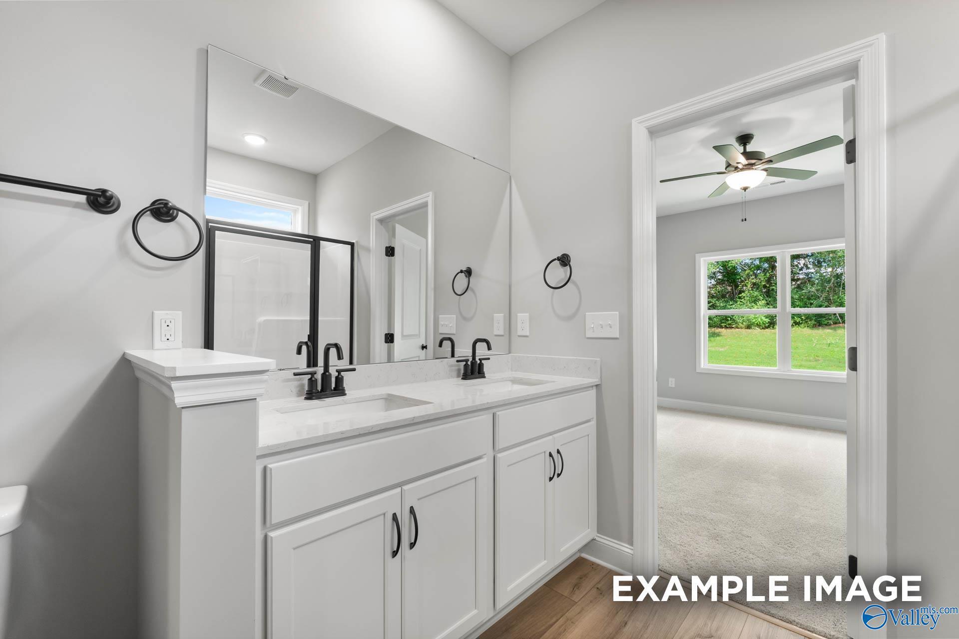 Modern master bathroom with double vanity, mirrors, and open door to bedroom in Davidson Homes The Asheville C, Hazel Green, AL