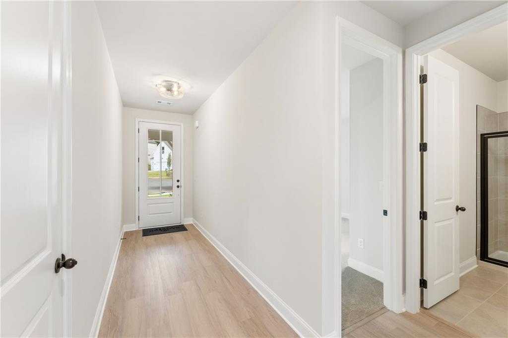 Bright entry hallway with glass front door, hardwood floors, white walls, and guest bath in Davidson Homes The Hickory B, Buford, GA