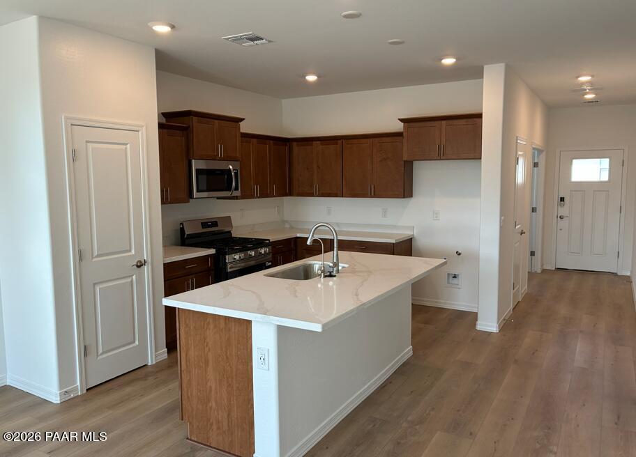 Open-concept kitchen with white quartz island, wood cabinetry, and stainless appliances in The Coronado A, Prescott, Arizona.