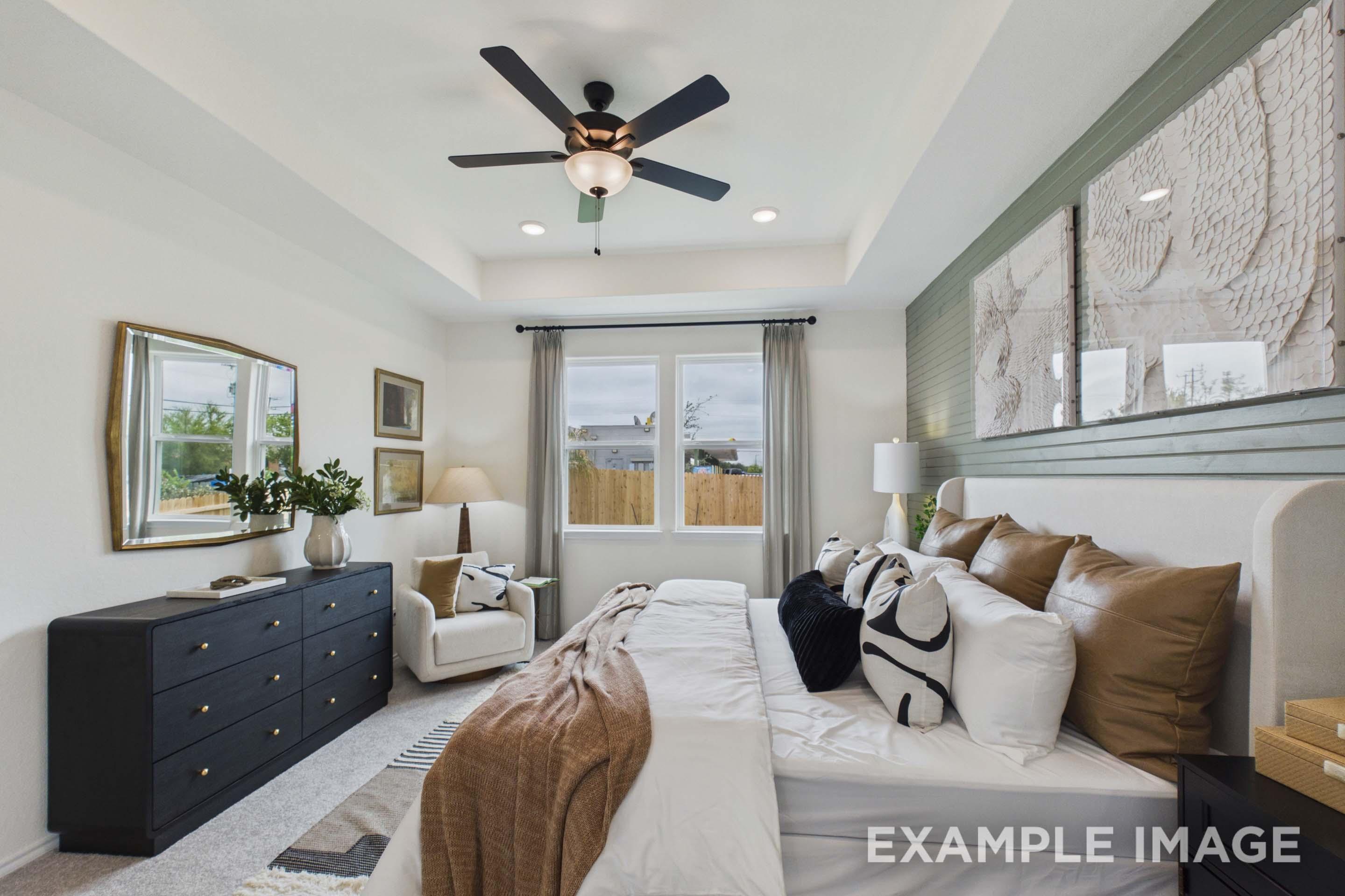 Spacious master suite on the main floor of The Laurel G featuring a tray ceiling, stylish accent wall, and modern decor.