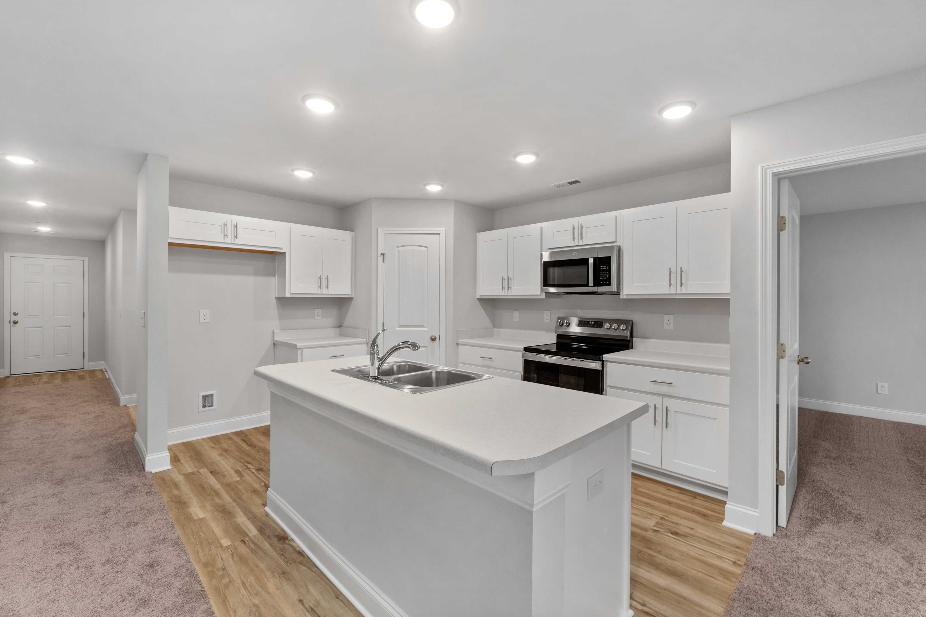 Bright white kitchen at Collins Lane in Meridianville, Alabama with center island, stainless steel appliances, and open layout