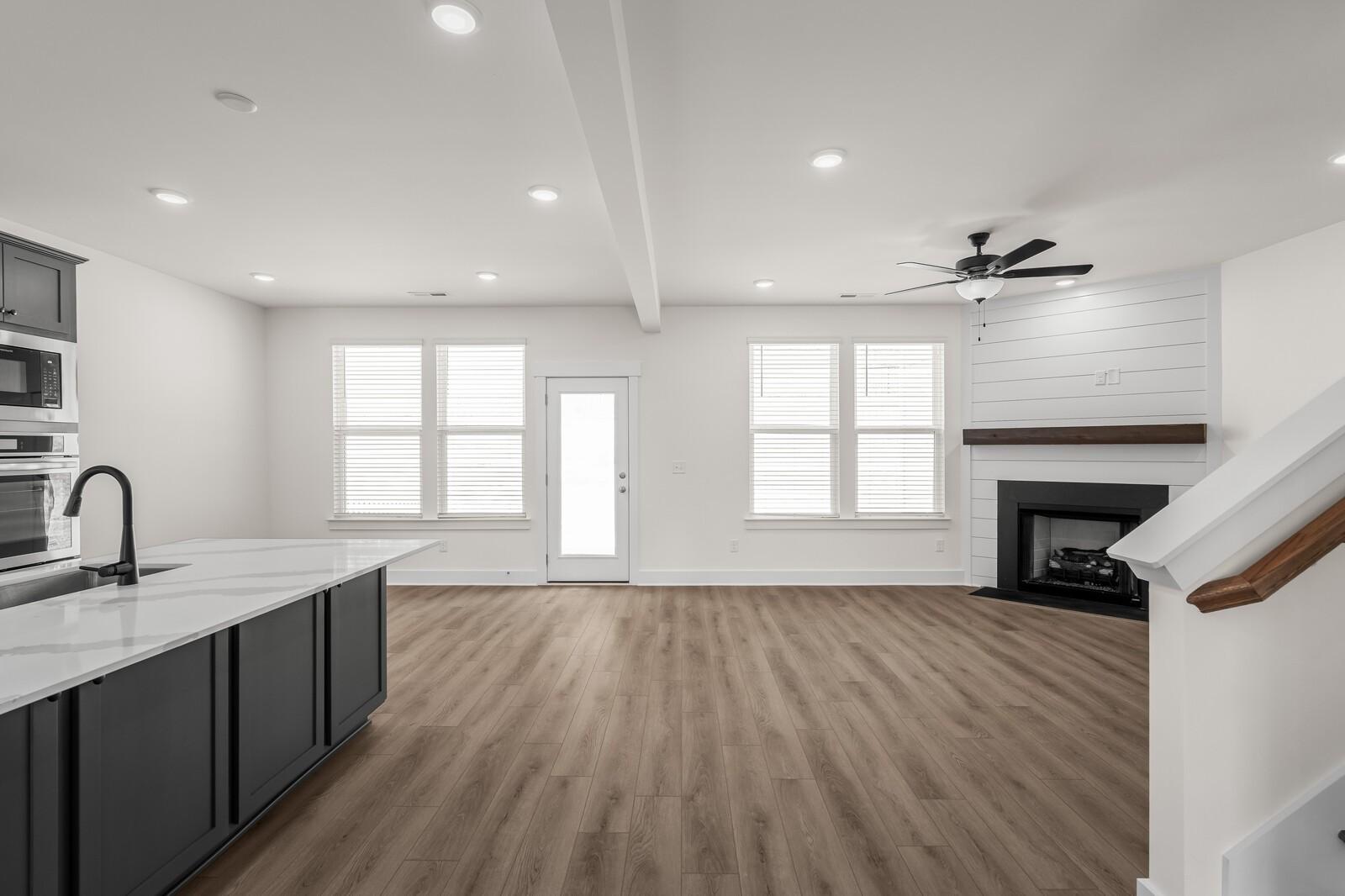 Open-concept living room and kitchen with fireplace in The Willow floor plan at Woods Crossing, Gallatin, Tennessee.