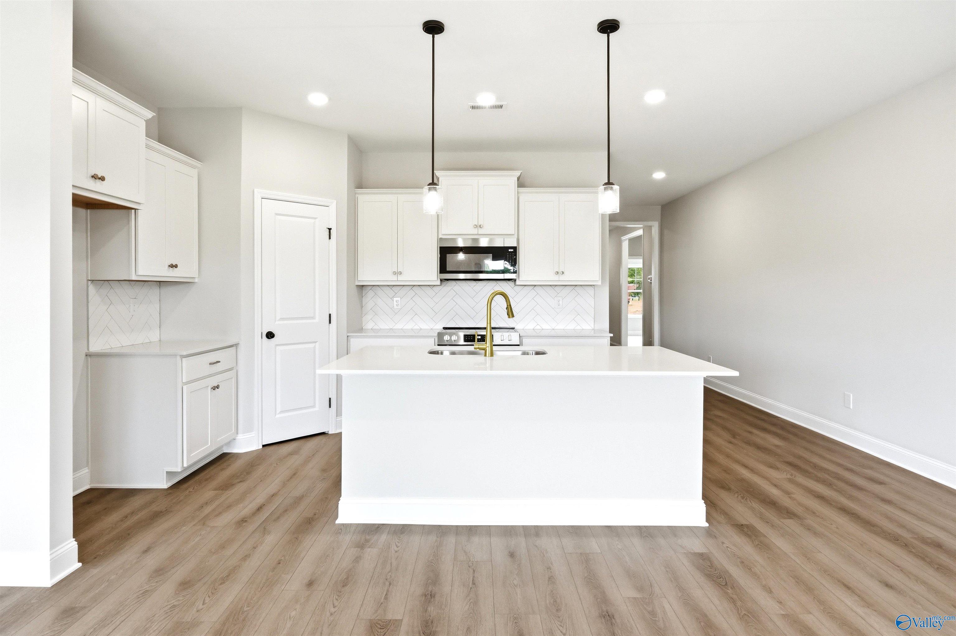 Modern kitchen with white cabinets, gold faucet, and island in The Daphne F plan at Berry Cove, New Market, Alabama.