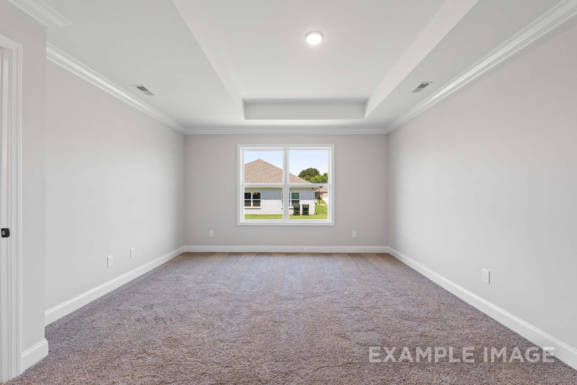 Spacious master bedroom in The Holly M home featuring light gray walls, beige carpet, recessed ceiling, and large backyard window