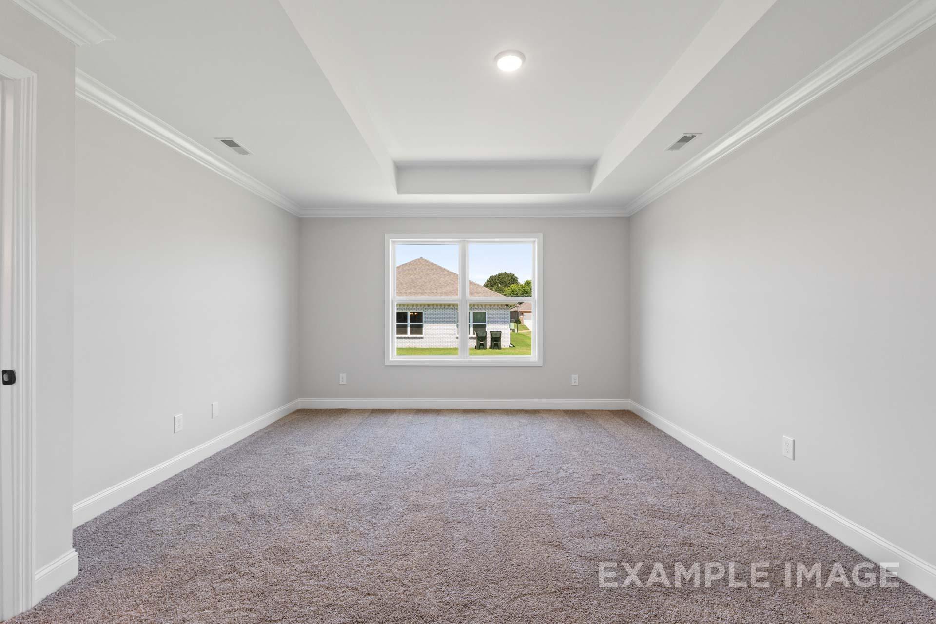 Spacious master bedroom in The Holly M home featuring light gray walls, beige carpet, recessed ceiling, and large backyard window