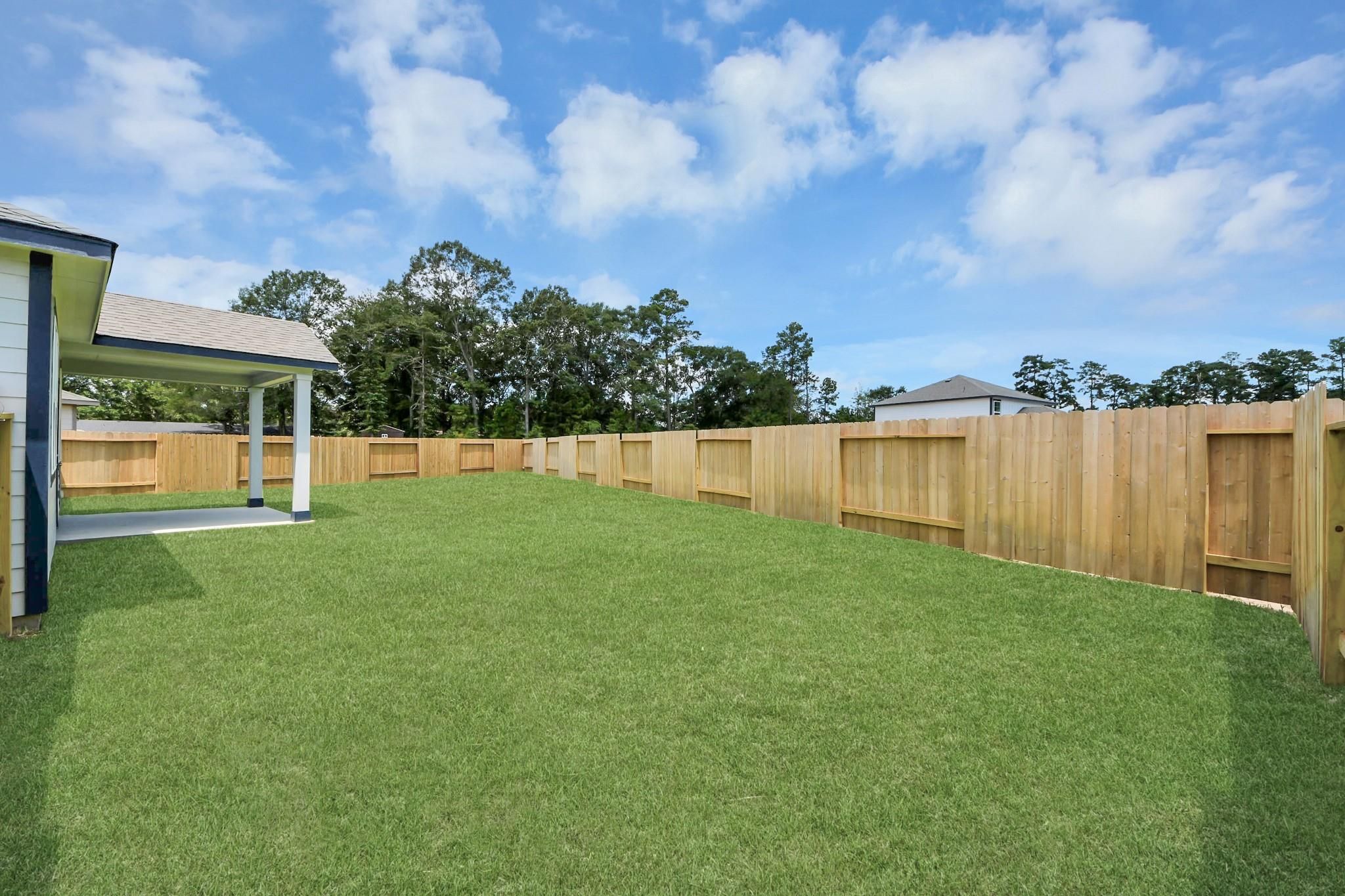 Spacious fenced backyard with covered patio at The Sabine F in Liberty Estates, Cleveland, Texas.