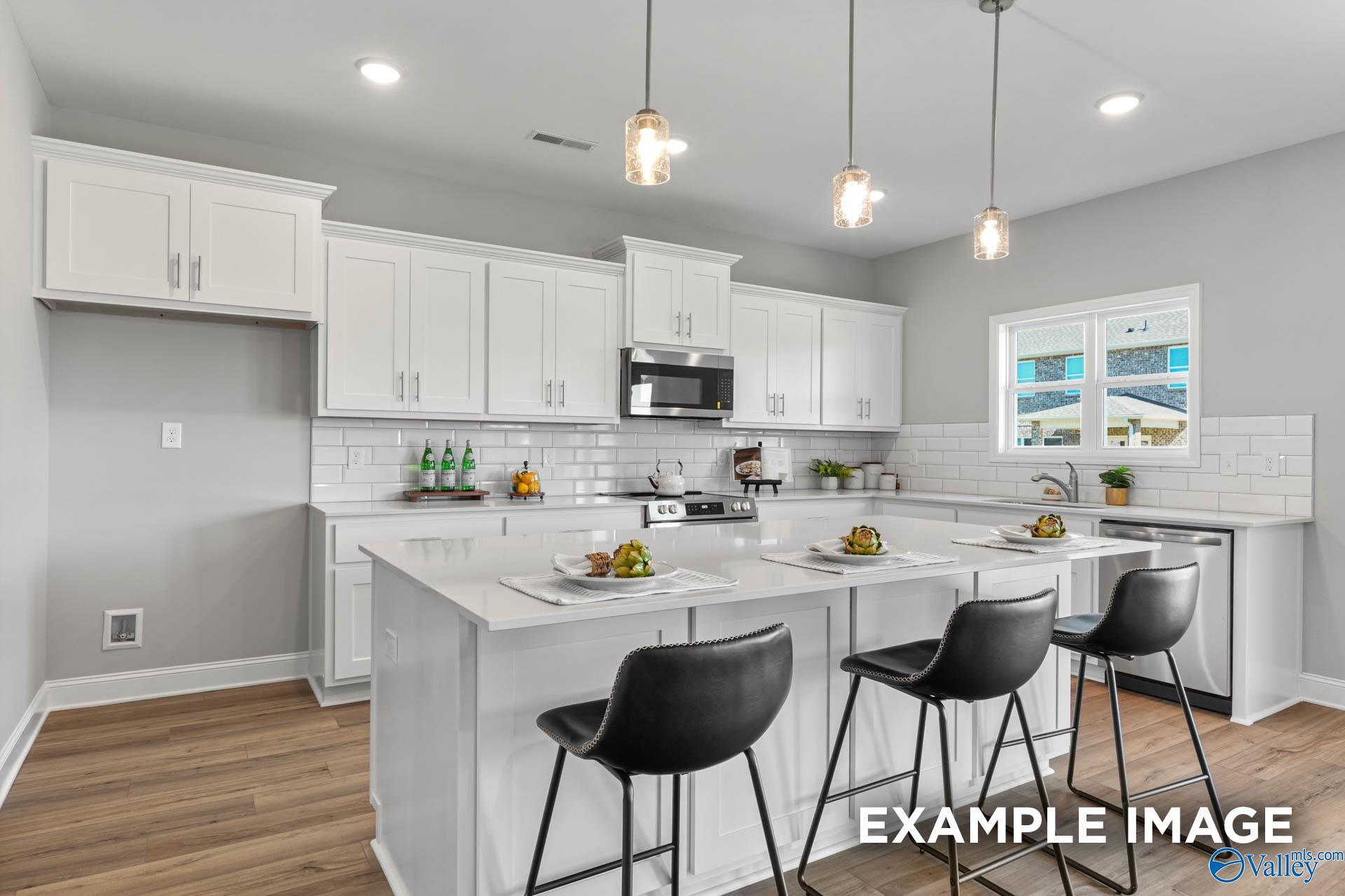 Modern white kitchen with shaker cabinets, stainless appliances, quartz island, subway tile backsplash in The Chelsea B, Ivy Hills, Toney, AL