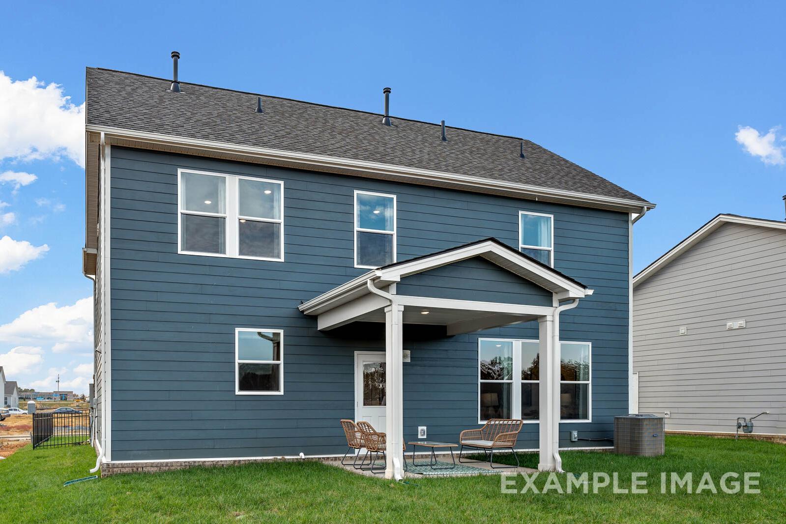 Two-story navy blue exterior of The Gordon C home with white-trimmed covered porch, patio chairs, and lush green lawn in White House, TN
