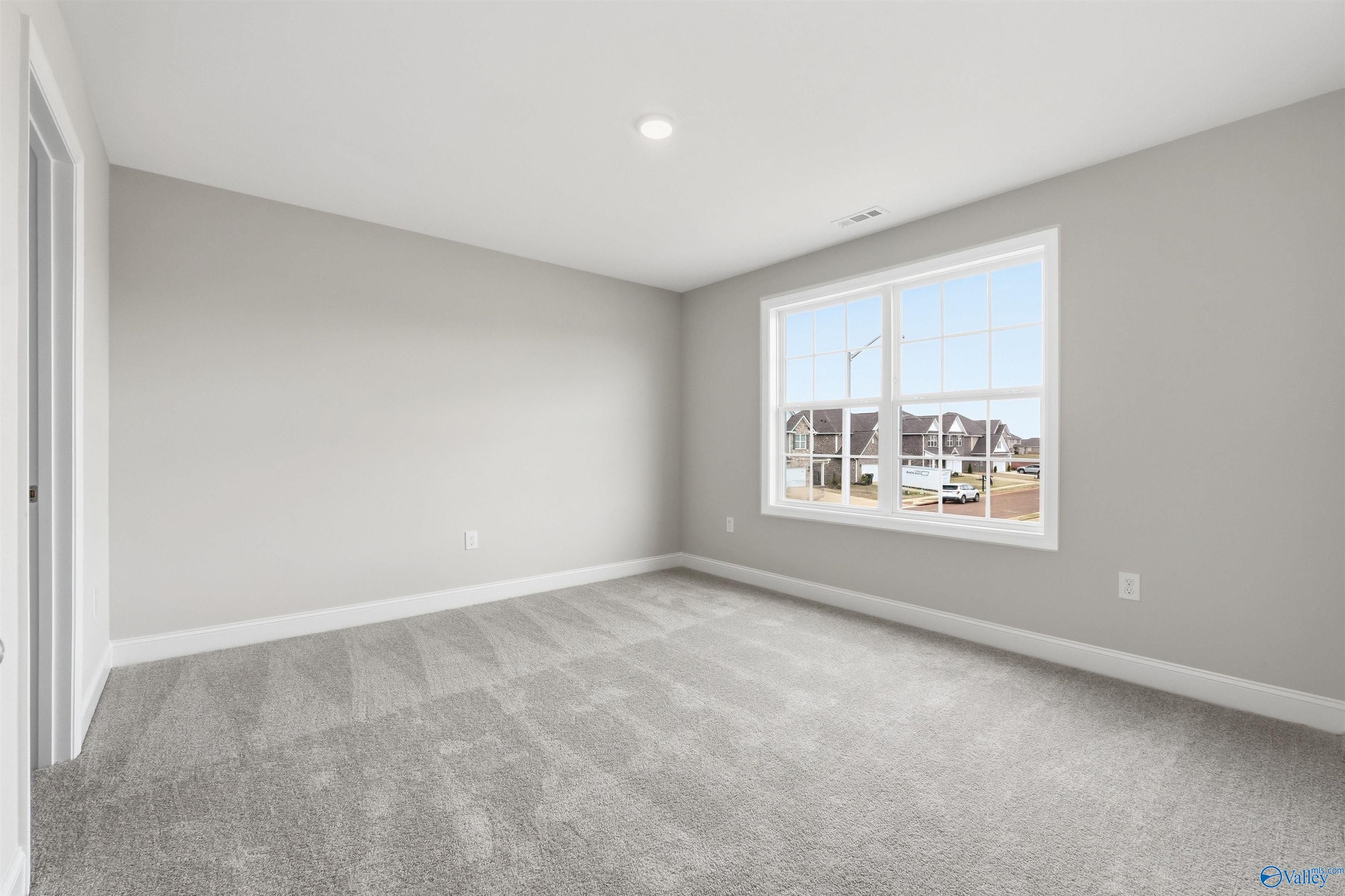 Spacious, neutral-toned bedroom with carpeted flooring in The Shelby D floor plan at Evergreen Mill, Madison, Alabama.
