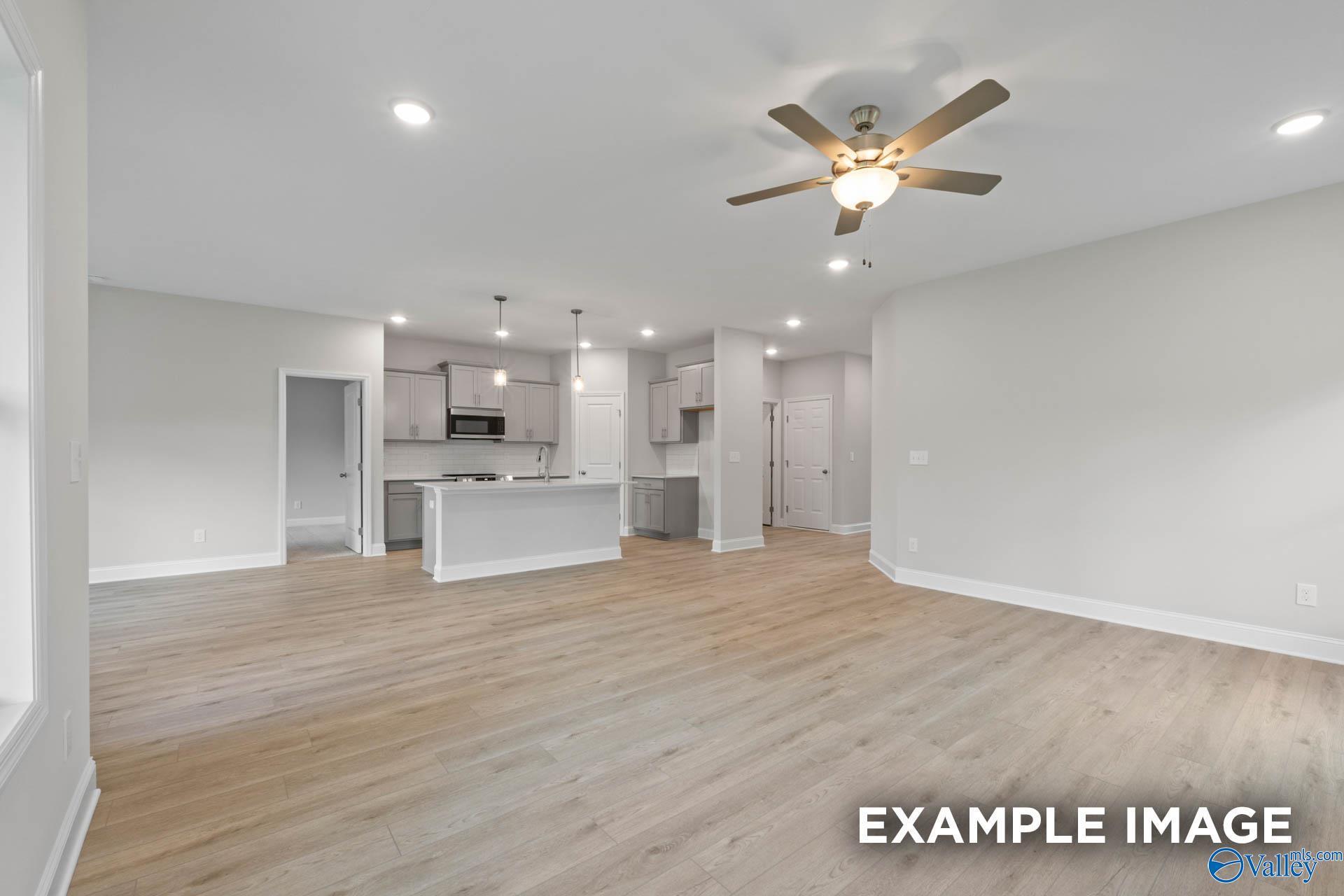 Open-concept living room and kitchen with wood-look flooring in The Franklin C floor plan, Walker's Hill, Meridianville.