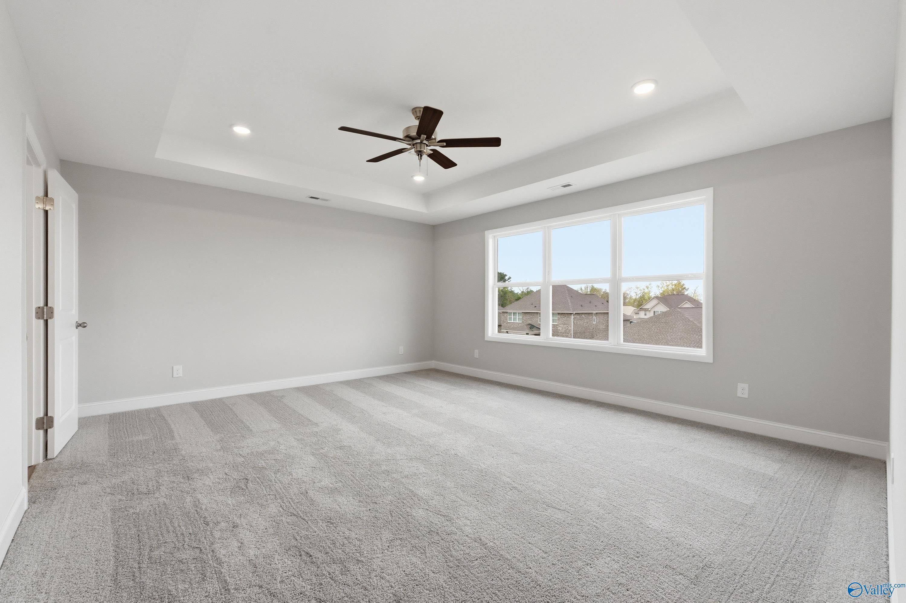 Spacious master bedroom with tray ceiling, ceiling fan, and large windows in Davidson Homes The Shelby B, New Market, Alabama