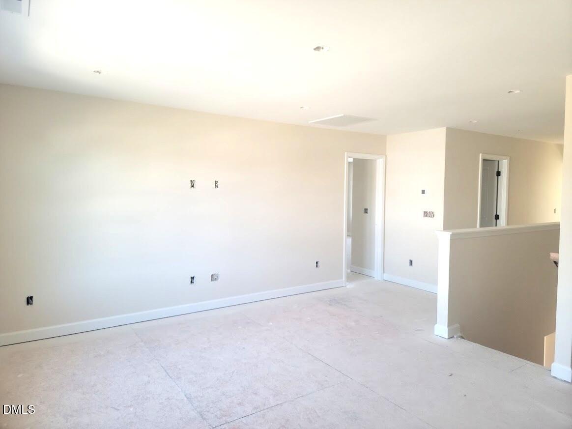 Spacious upstairs hallway with beige walls, doors, and open railing in Davidson Homes The Cypress B II, Angier, NC