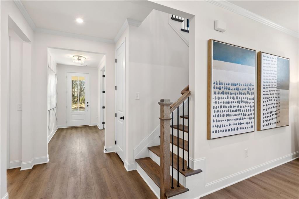 Bright foyer hallway with hardwood floors, wrought iron staircase, and abstract blue art in Davidson Homes The Aspen A, Buford, GA
