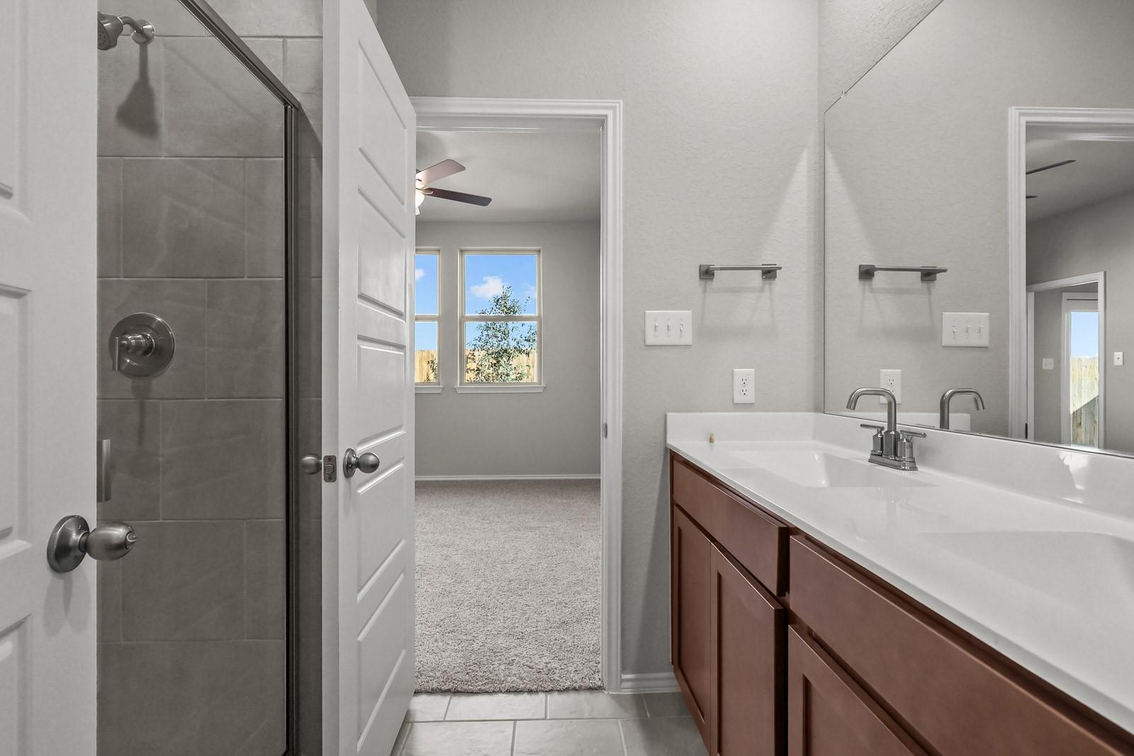 Modern bathroom with dual vanity and glass-enclosed shower in The Frio G floor plan by Davidson Homes in Heartland, Texas.