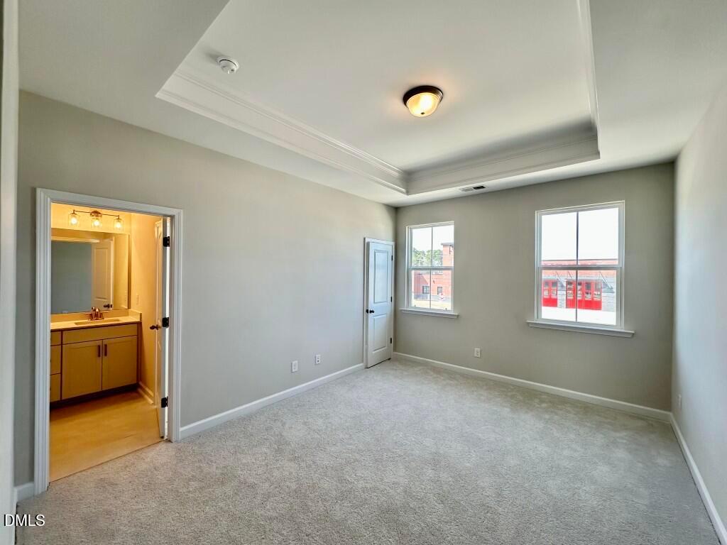 Spacious master bedroom with en-suite bathroom, tray ceiling, and windows in Davidson Homes The Burke, Knightdale, NC