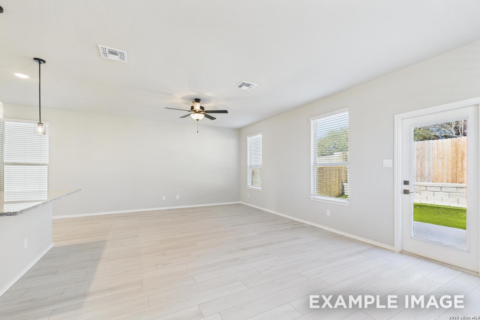 Bright open-concept living area with wood-look flooring in The Charlotte B floor plan at Cedar Heights, San Antonio.