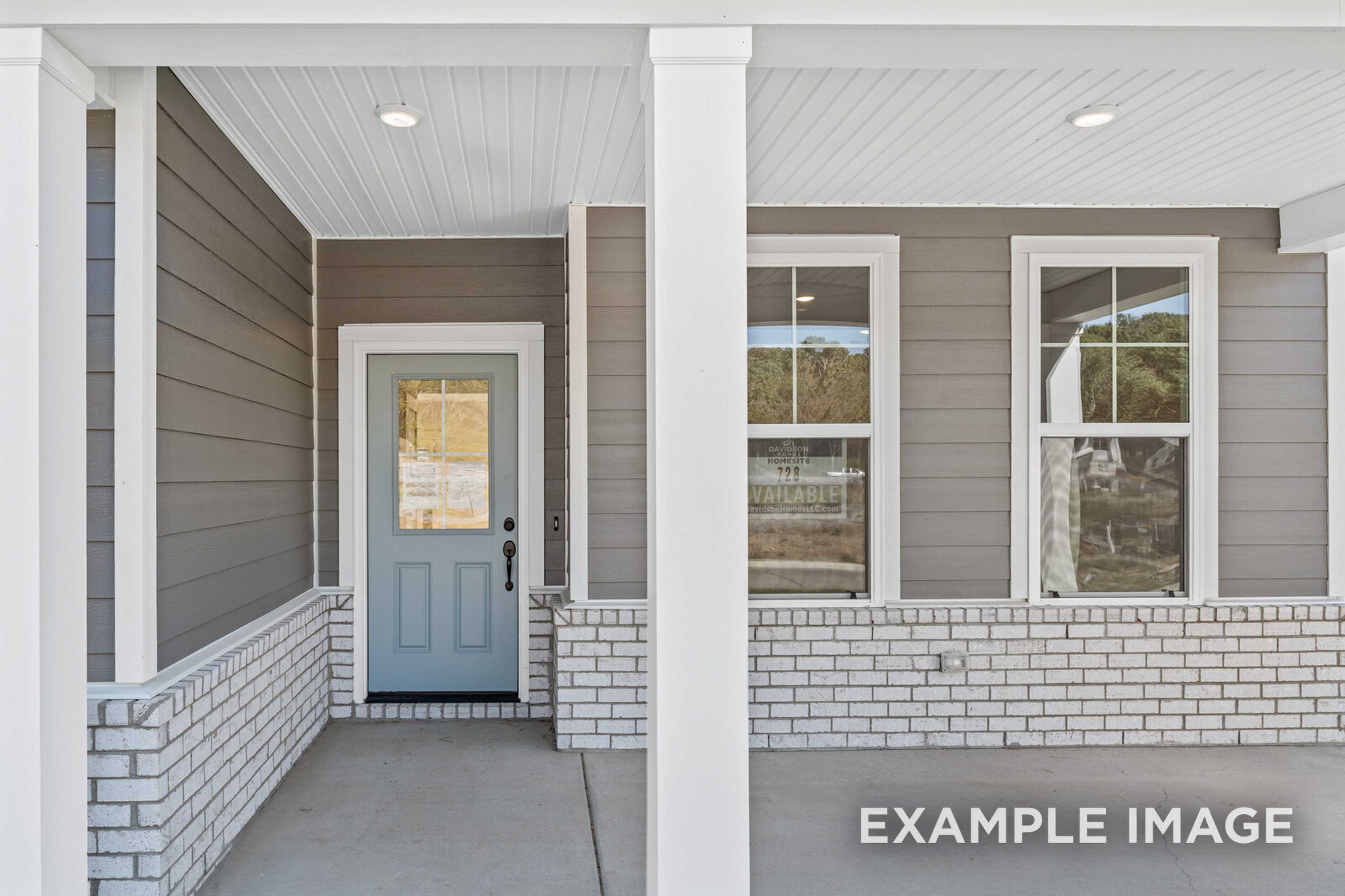 Front elevation of The Henry C 2-story home with covered porch, gray siding, white columns, brick accents, and blue glass door