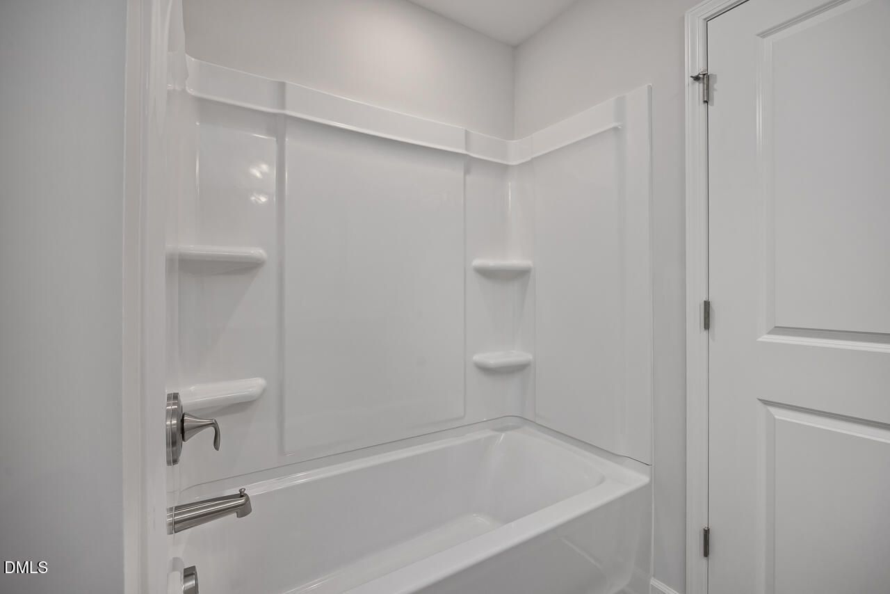 Modern white bathtub and wall surround in a 3-bath Adalynn B floor plan home at Gregory Village in Lillington, NC.