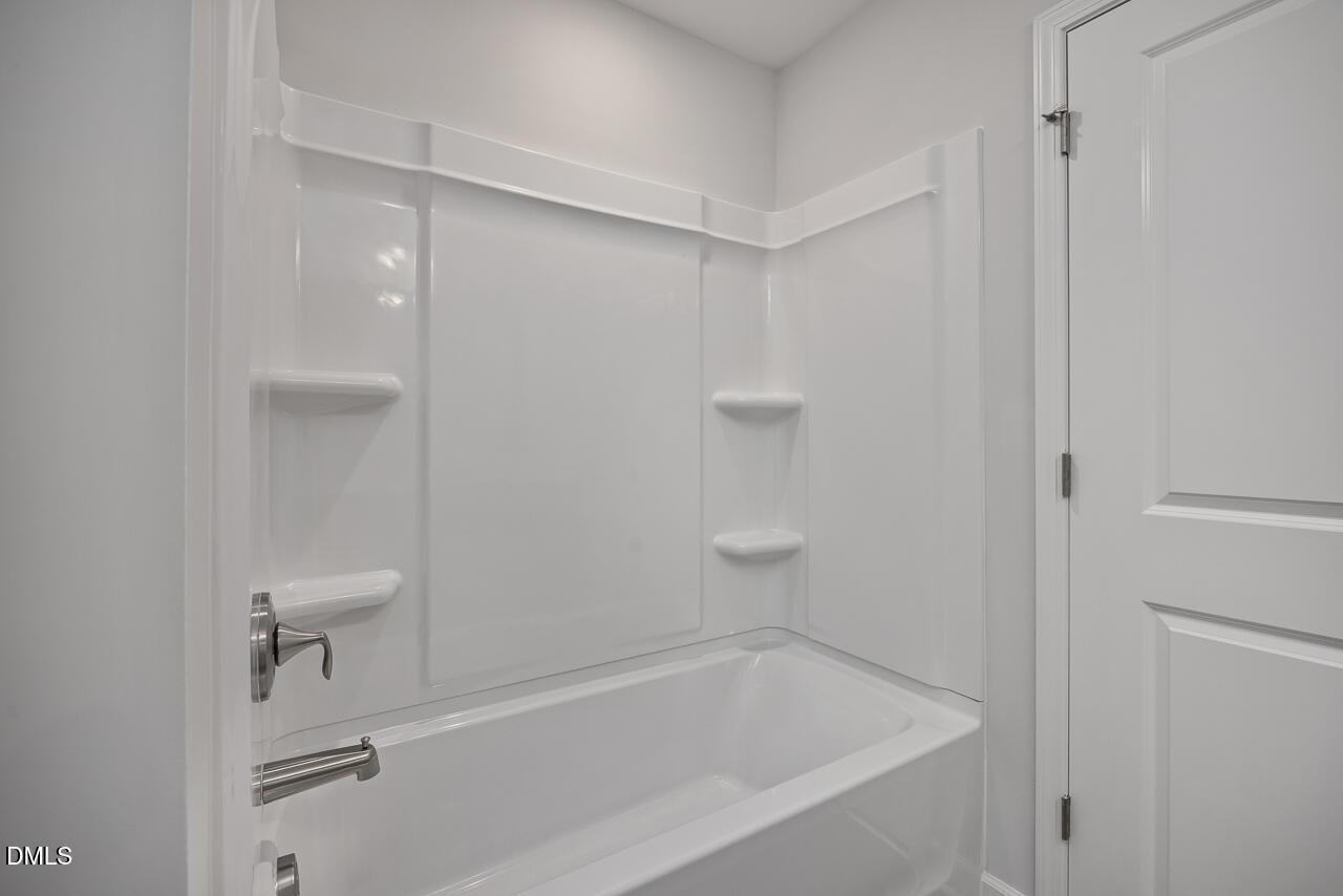 Modern white bathtub and wall surround in a 3-bath Adalynn B floor plan home at Gregory Village in Lillington, NC.