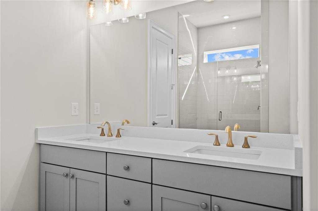 Luxurious master bathroom double vanity in gray cabinets with gold faucets, frameless glass shower in Davidson Homes The Arlington A, East Cobb